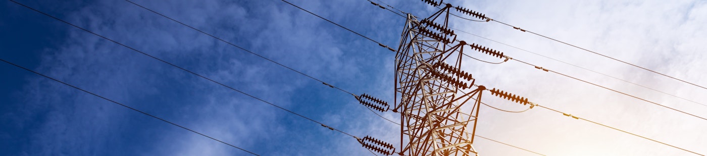 photo from the perspective of looking up to the top of electricity tower pylons with a colorful blue and yellow background in the sky